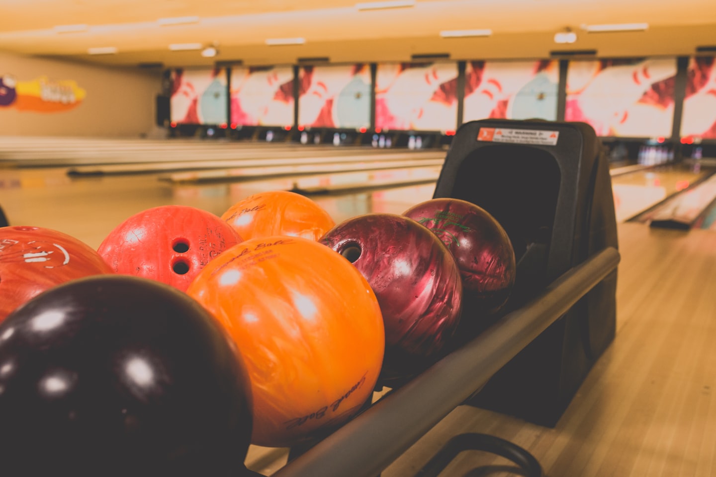 Bowlingkugeln vor einer Bowlingbahn.